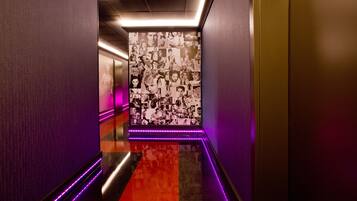 A hallway with a reflective floor, purple LED lighting, and a wall adorned with black and white photographs.
