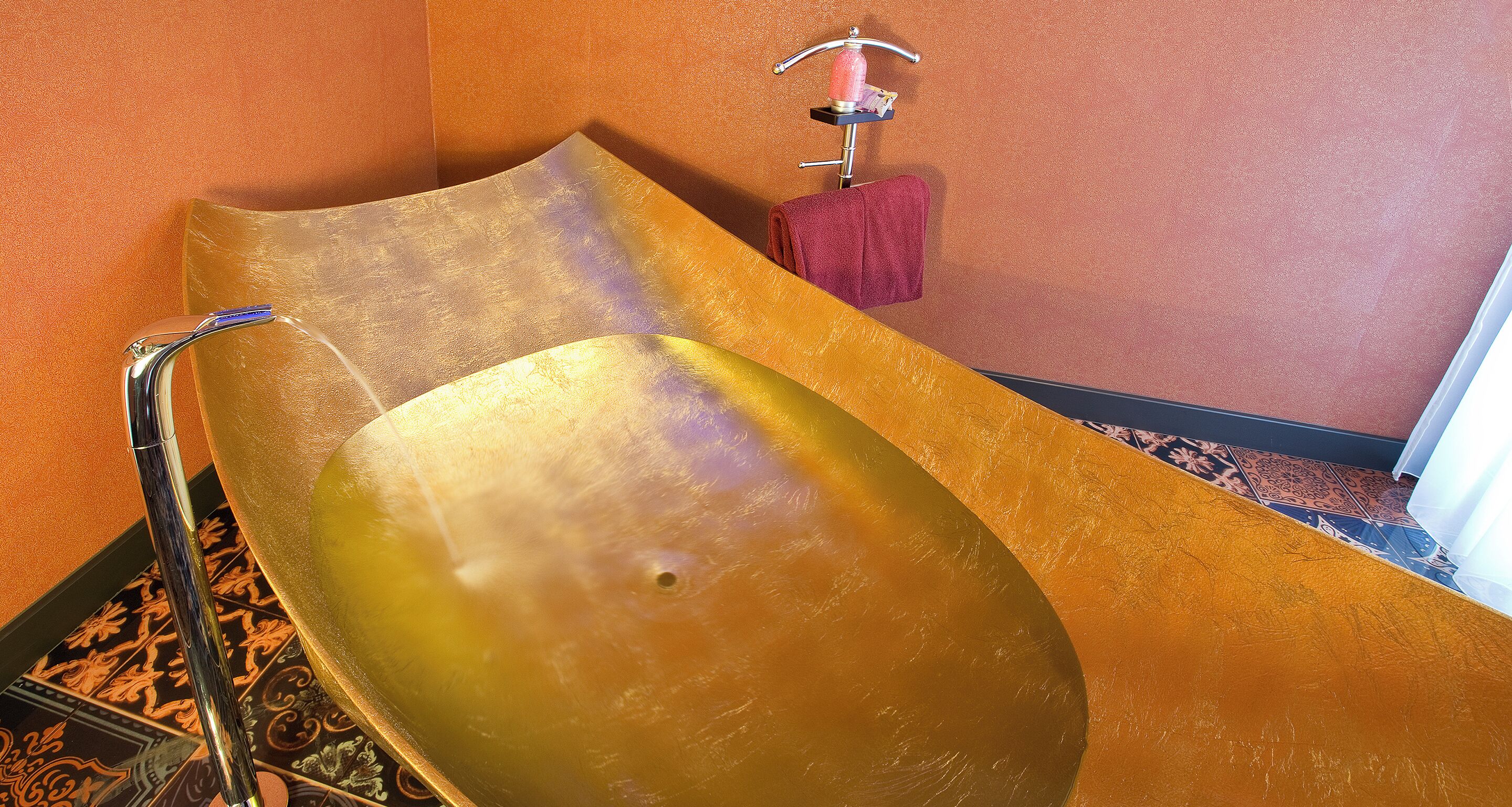 Eine Badewanne mit modernem Design, ein Handtuchhalter mit einem roten Handtuch und ein strukturierter Boden.