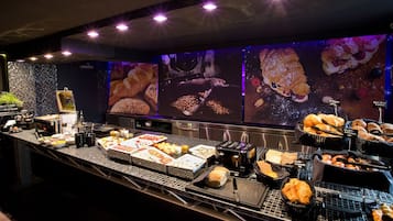 A buffet with various food items and a large screen displaying food images.