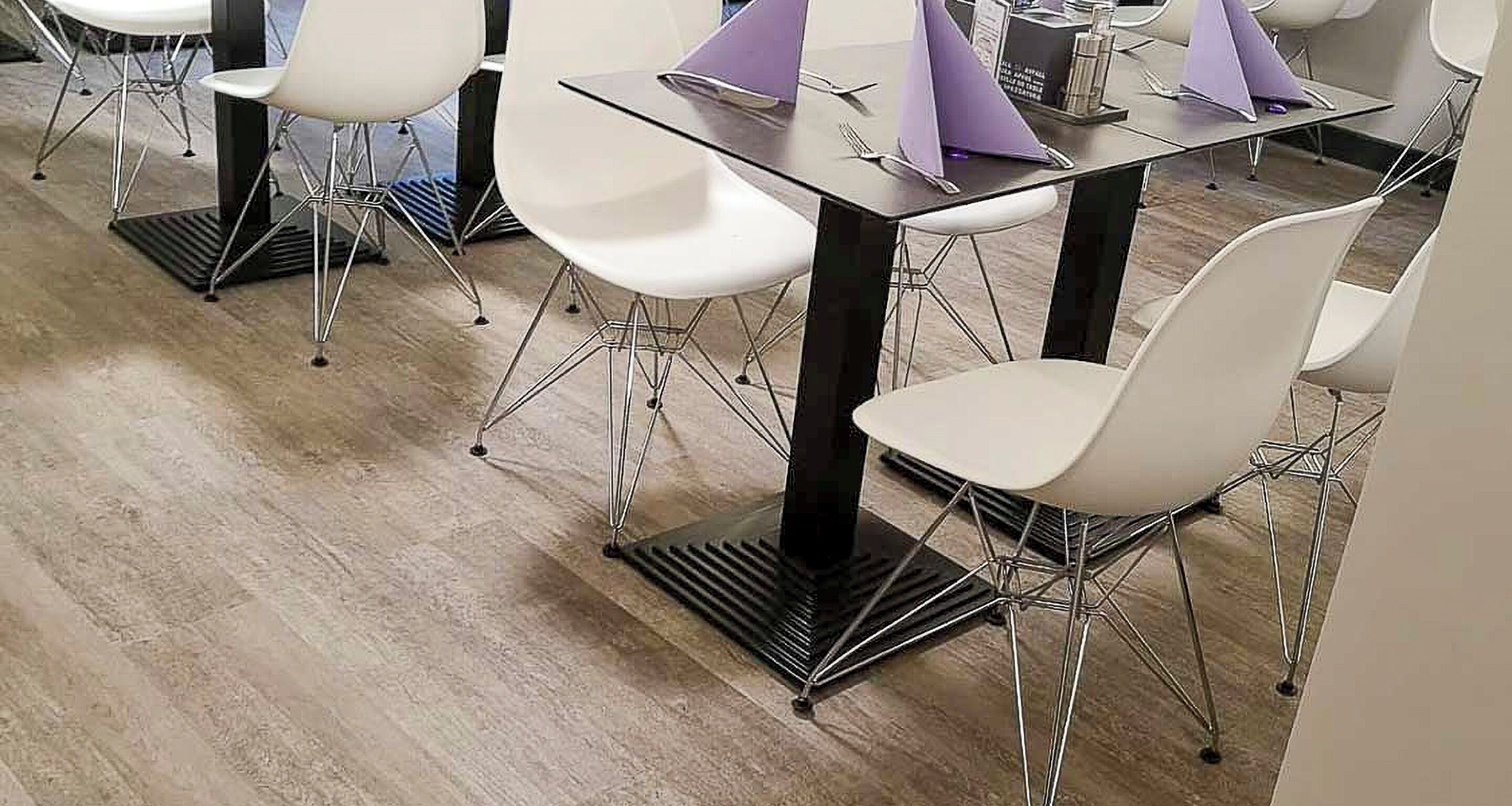 Un comedor moderno con sillas blancas y mesas negras, que presenta un diseño limpio y contemporáneo.