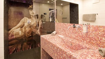 Un baño con lavamanos con azulejos, un espejo y un toallero.