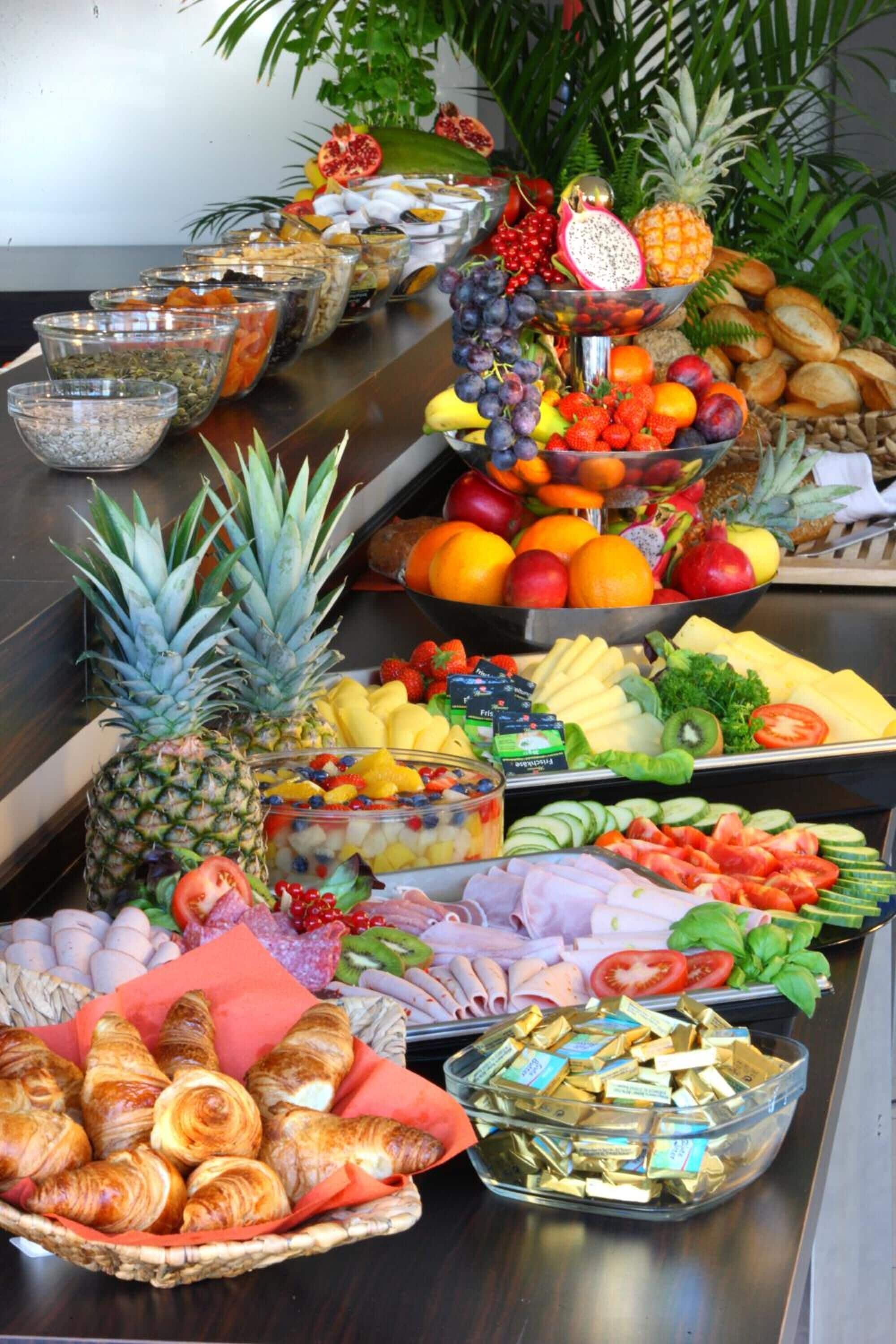 Un bufé con diversas frutas, verduras y pasteles.