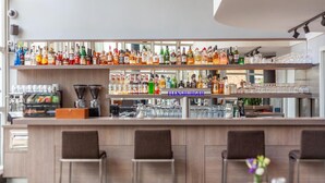 A bar area with multiple shelves of liquor bottles, a coffee machine, and bar stools.
