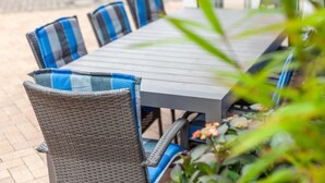 A dining table with wicker chairs, some with blue cushions.