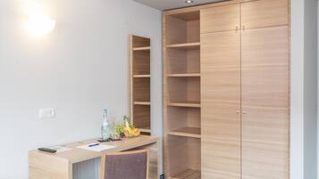 Habitación de hotel con escritorio de madera, una silla, armario y espejo.