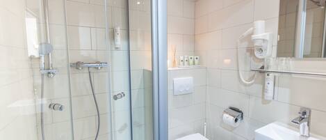 Une salle de bain moderne avec une douche à parois de verre, des toilettes blanches, un lavabo et un miroir.
