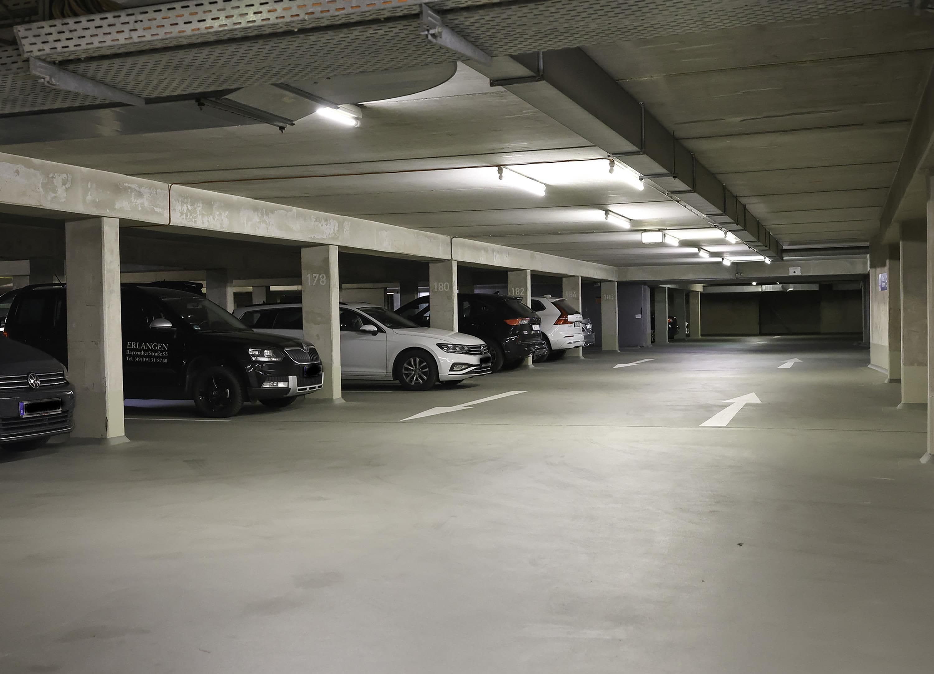 Eine mehrstöckige Tiefgarage mit Betonsäulen und Deckenbeleuchtung.