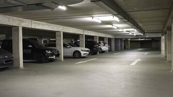 Garagem subterrânea com vários níveis, pilares de concreto e iluminação superior.