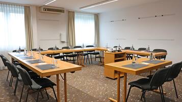 Ein Konferenzraum mit einem U-förmigen Tisch, schwarzen Stühlen, Wasserflaschen und einem Projektor.