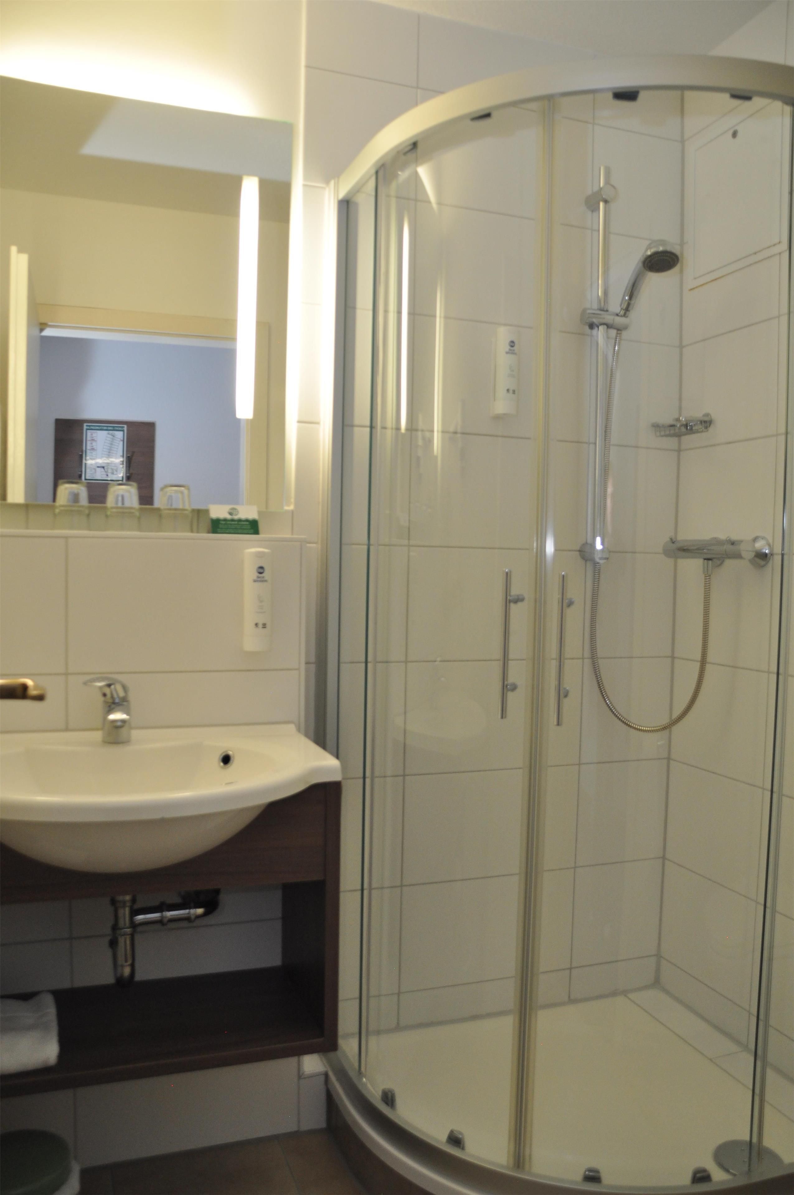 A modern bathroom with a glass-enclosed shower, a white sink, and a mirror above the sink.