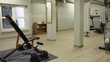 Un gimnasio con equipo de ejercicio, una ventana y un estante de madera.