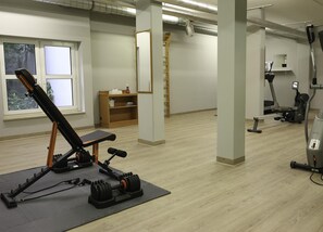A gym with exercise equipment, a window, and a wooden shelf. - Best Western Hotel Erlangen (Erlangen)