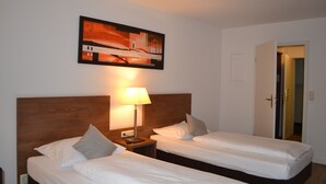 A hotel room with two single beds, a wooden headboard, a nightstand with a lamp, and a painting on the wall. - Best Western Hotel Erlangen (Erlangen)