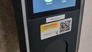 Un quiosco de autoservicio con una pantalla que muestra opciones de idioma y un código QR para pago sin contacto.
