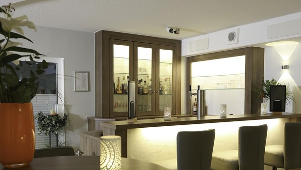 A modern kitchen with a bar area, a dining table with chairs, and a potted plant. - Best Western Hotel Erlangen (Erlangen)