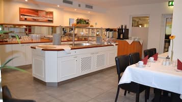 Ein Restaurant mit einer zentralen Inselbar, weißen Schränken und einem Essbereich mit gedeckten Tischen.