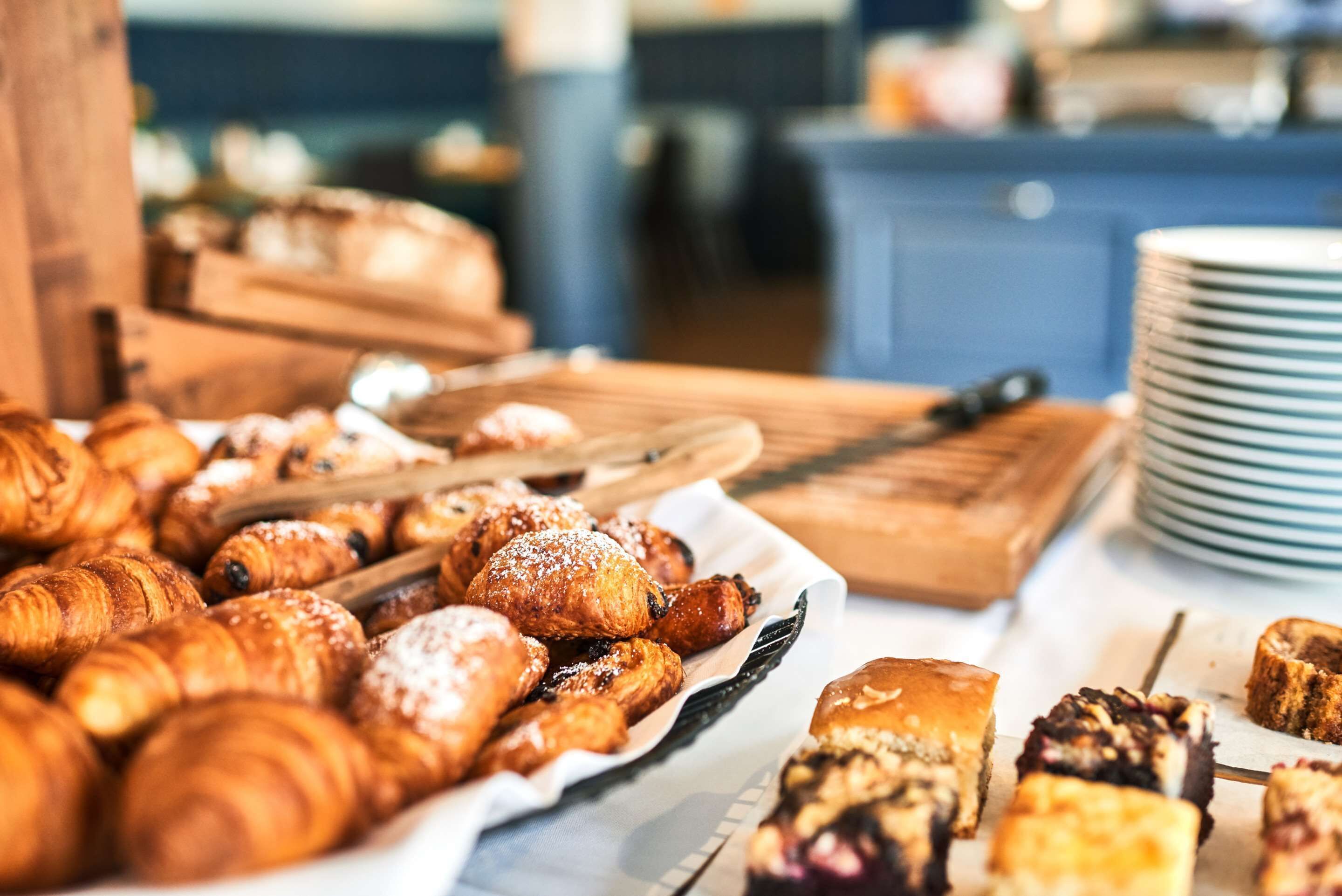 Une variété de viennoiseries et de pâtisseries sont disposées sur une table, notamment des croissants et d’autres douceurs.