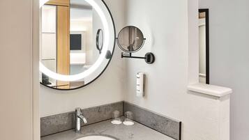 Un baño moderno con un espejo redondo, un lavamanos y un perchero para toallas.