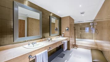 Une salle de bain moderne avec deux lavabos, de grands miroirs, une douche à parois de verre et un banc.