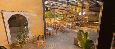 A restaurant with a glass ceiling, wooden furniture, and a fireplace.