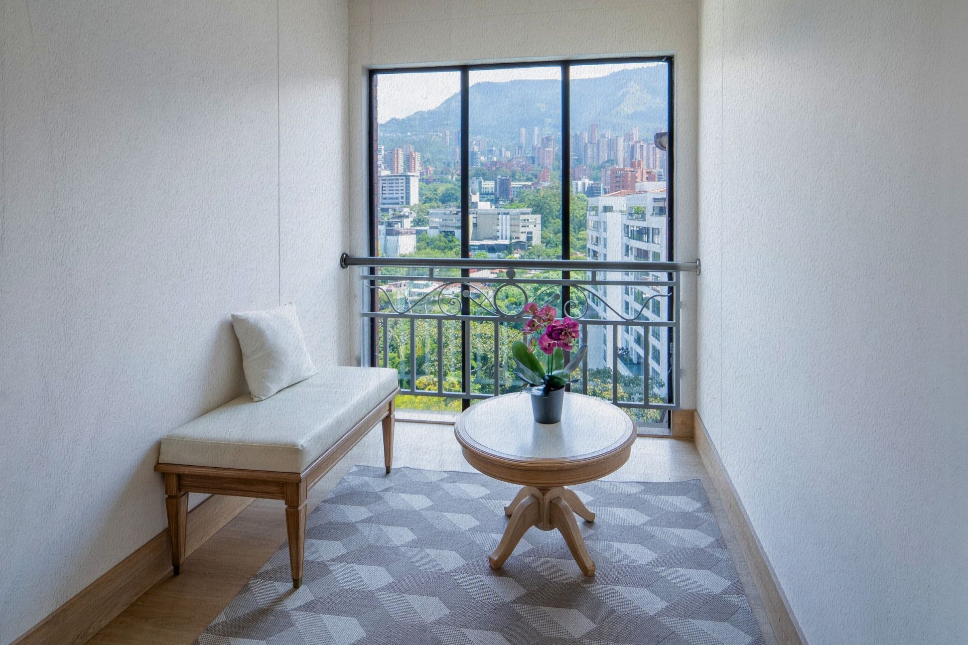 Un balcon avec un canapé et une table, une vue sur le paysage urbain et une plante en pot.