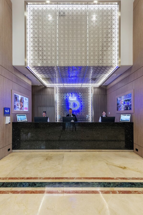 A reception desk with three employees, a large illuminated wall, and a digital screen displaying a cityscape.