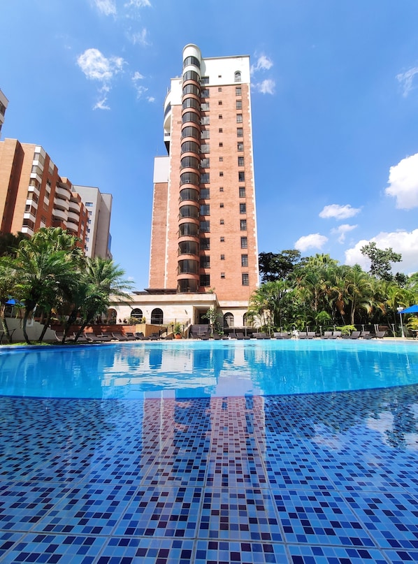 Una piscina al aire libre, sombrillas, sillones reclinables de piscina