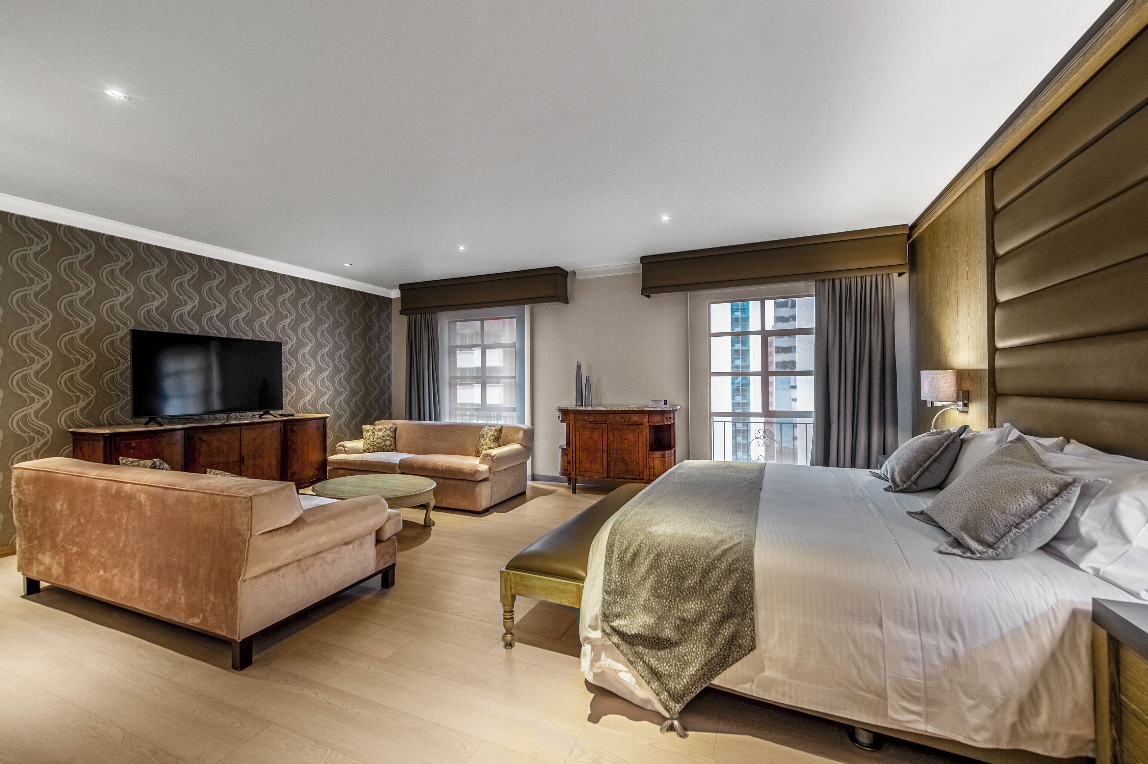 Una habitación de hotel moderna con una cama grande, un sofá, un televisor y un escritorio.