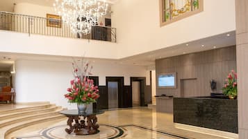A spacious lobby with a grand chandelier, a reception desk, and a large stained glass window.