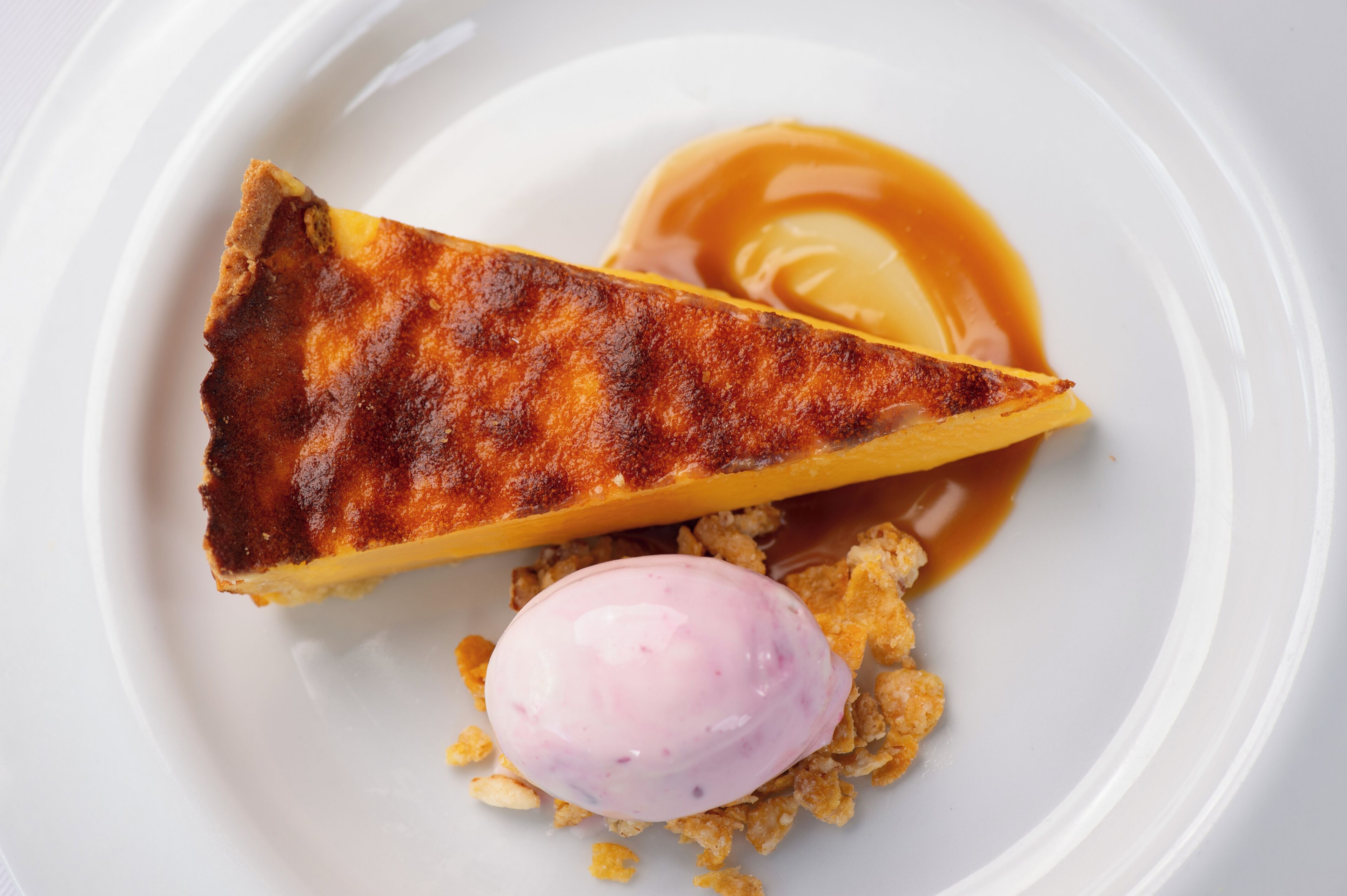 A dessert plate with a caramelized tart, a scoop of ice cream, and caramel sauce.