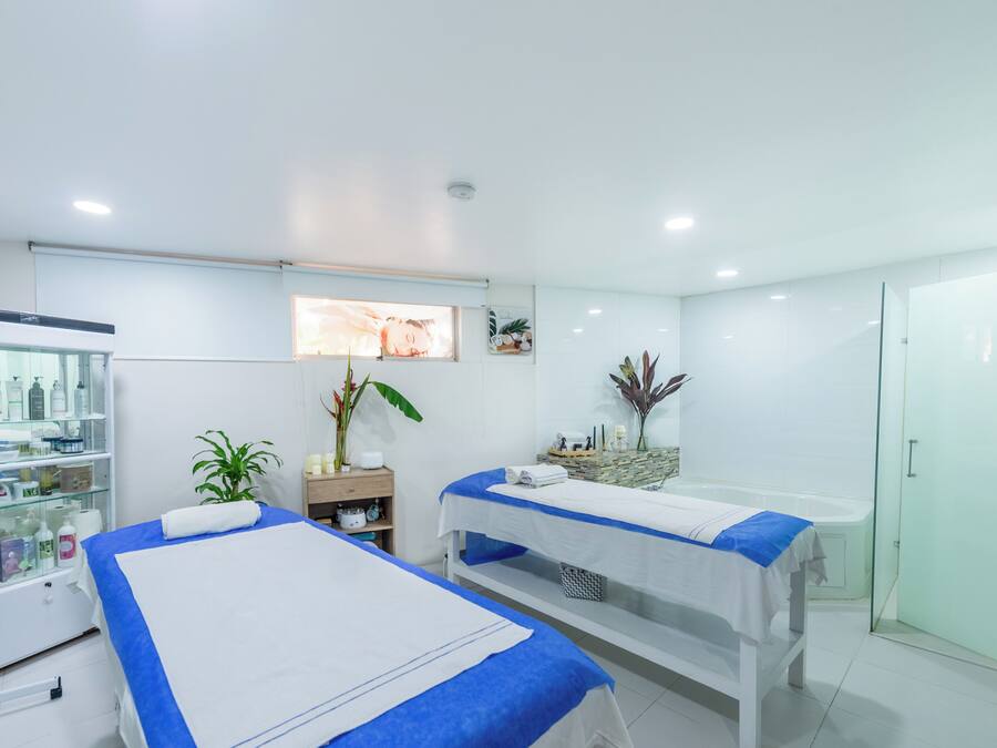Un moderno spa con dos camillas, una zona de recepción y un box de ducha de vidrio.