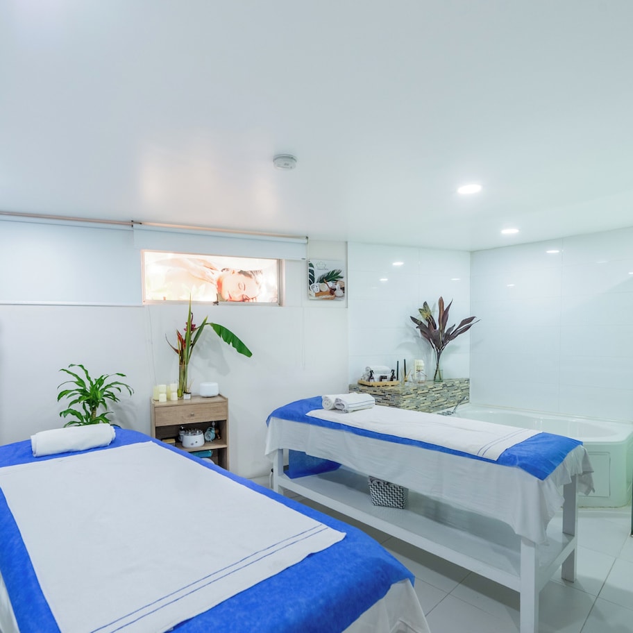 A modern spa room with two beds, a reception area, and a glass shower enclosure.