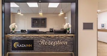 A reception area with a stone wall, a 'Plaza Inn' sign, and two reception desks.