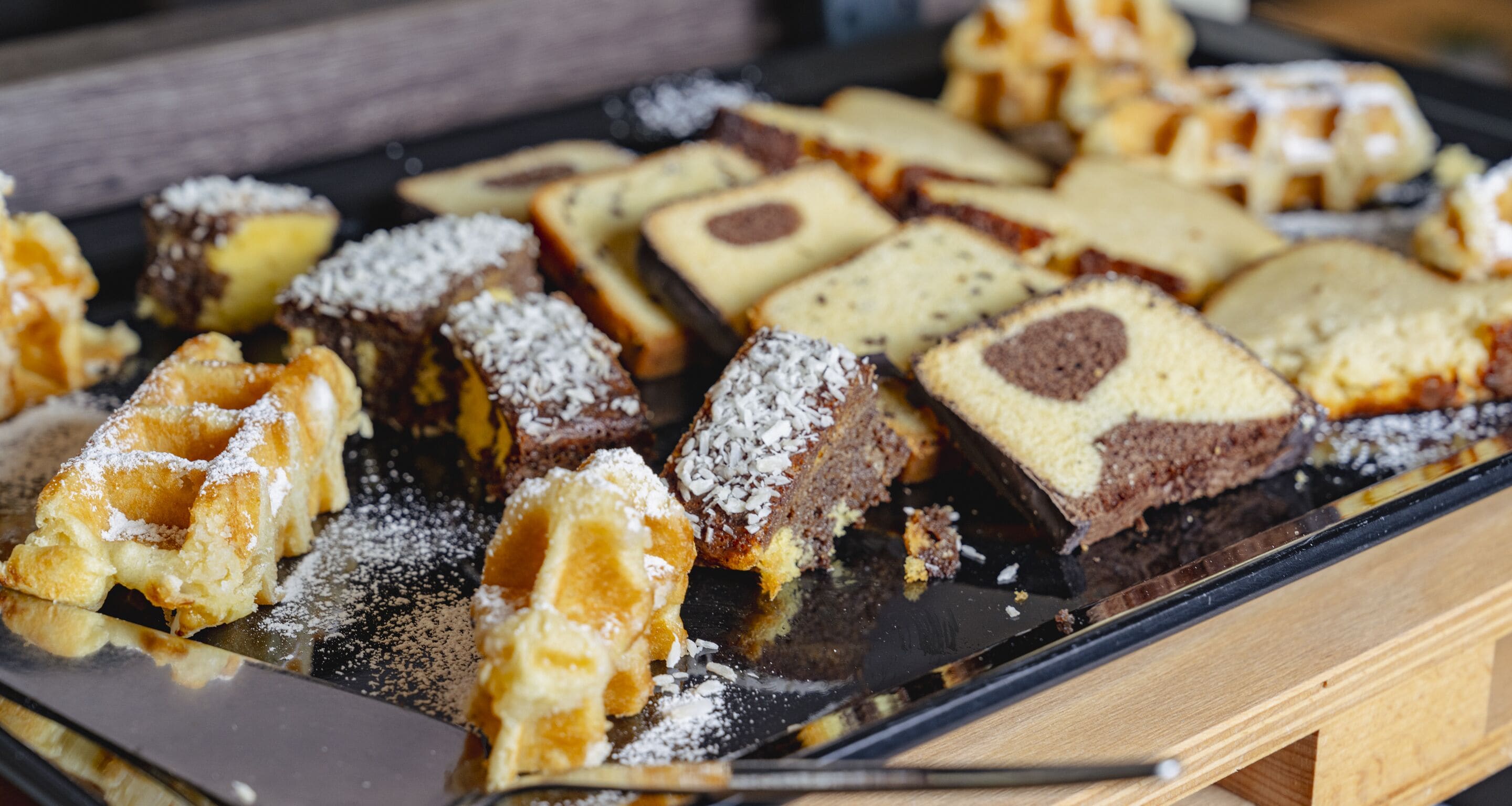 Diversas pastas en una bandeja, incluyendo pan con cobertura de chocolate y coco.