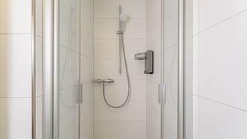 Una ducha moderna con cabezal de ducha manual y panel de control en la pared.