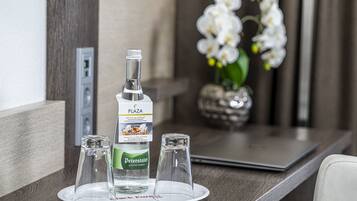 A minibar setup with a bottle of Peterstaler, two glasses, and a laptop on a tray.
