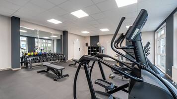 A gym with treadmills, dumbbells, and benches.