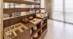 A breakfast buffet setup with bread, pastries, and utensils. - PLAZA INN Karlsruhe Nord (Karlsruhe)