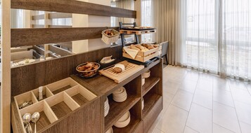 A breakfast buffet setup with bread, pastries, and utensils.