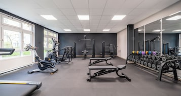 A gym with cardio machines, weightlifting equipment, and dumbbells.