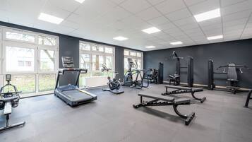 A modern gym with treadmills, weight machines, and exercise mats.
