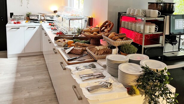Een buffetopstelling met diverse gerechten, borden en bestek.