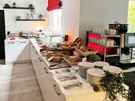 Montaje de bufé con diversos alimentos, platos y cubiertos.