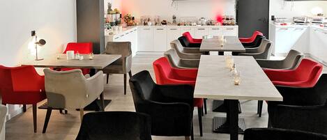 Un comedor moderno con varias mesas y sillas, una cocina al fondo y una decoración minimalista.
