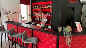 Een bar met rode bekleding, een toonbank met verschillende flessen en glazen, en een bord met de tekst 'NIERO'.