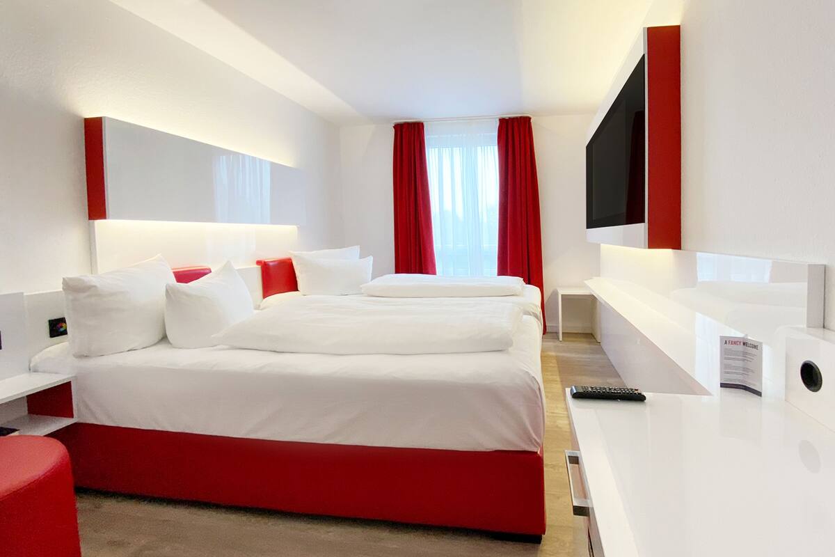 Ein modernes Hotelzimmer mit einem großen Bett, einem Schreibtisch und einem Fernseher.
