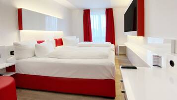 Una habitación de hotel moderna con una cama grande, un escritorio y un televisor.
