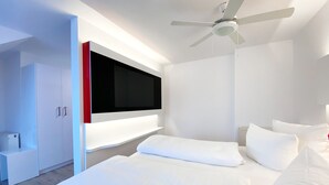 Een moderne slaapkamer met een groot bed, een flatscreen televisie aan de muur en een plafondventilator.