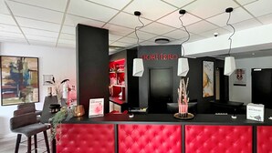 Een receptiebalie met een rood, gestoffeerd ontwerp, een zwarte toonbank en een bord met de tekst 'DORMIRE'.