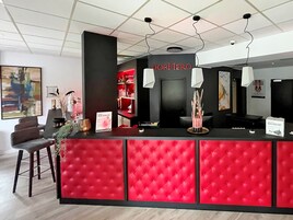 Un mostrador de recepción con diseño capitonado rojo, una barra negra y un letrero que dice "DORMIRE".